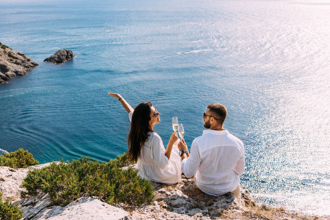 a happy couple sitting on vacation cheering champagne while their taxes are being handled